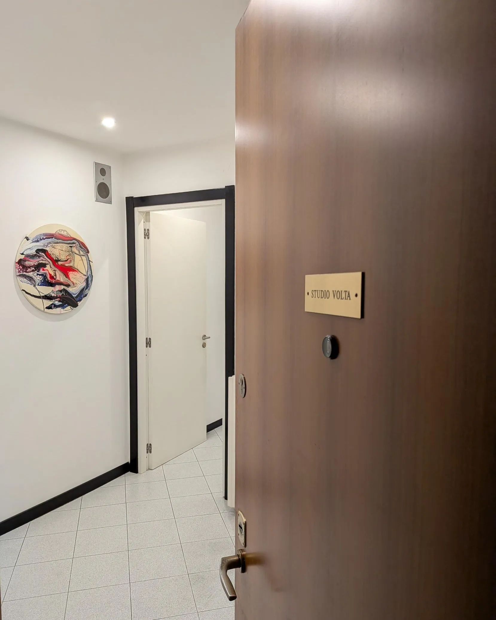 La porta d’ingresso di Studio Volta con la targa, aperta sul corridoio dello studio